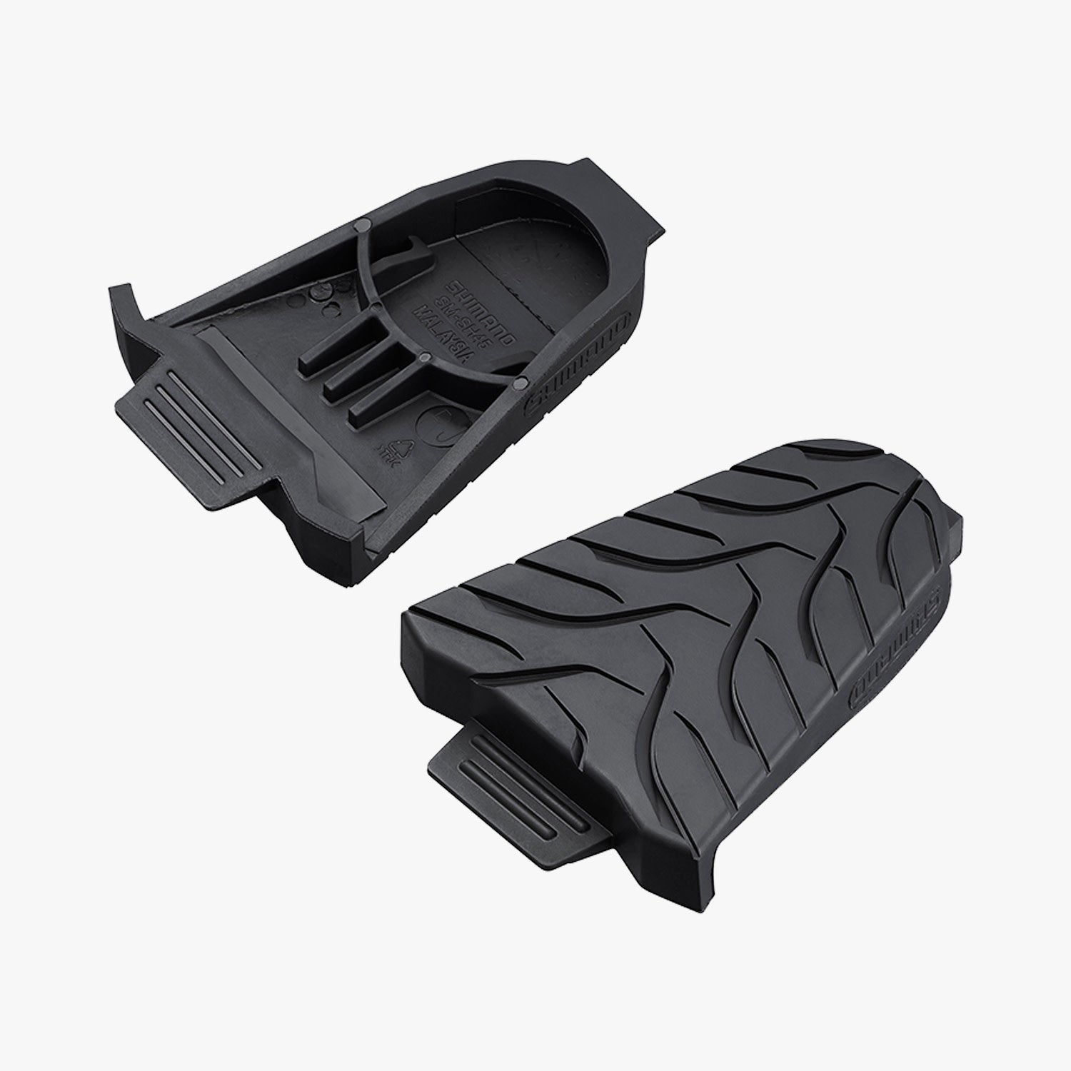 Дві чорні захисні накладки Shimano SM-SH45 SPD-SL, розташовані окремо одна від одної, з видимими рельєфними малюнками на поверхні для забезпечення кращого зчеплення та стійкості.